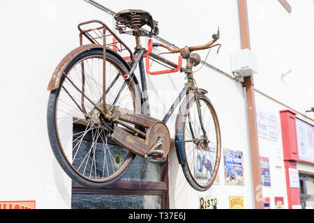 Ein Fahrrad- und ein altmodisches Metall werbeschilder an der Wand außerhalb eines Irish Shop. Stockfoto