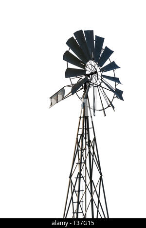 Niedrige Winkel Ansicht einer altmodischen, mehrblättrigen, Metall-Windpumpe auf einem Gitterturm in Hintergrundbeleuchtung, isoliert auf weißem Hintergrund. Stockfoto