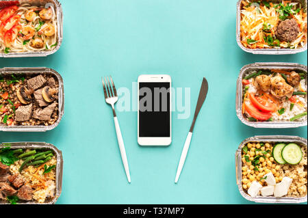 Täglichen Mahlzeiten in Folie Boxen und Smartphone auf blauem Hintergrund, Ansicht von oben, kopieren. Gesundes Essen Lieferung Konzept. Fitness Ernährung Ernährung. Stockfoto