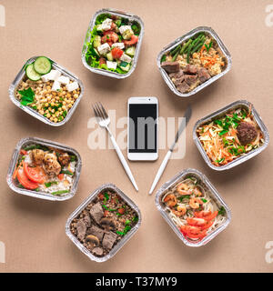 Täglichen Mahlzeiten in Folie Boxen und Smartphone, Ansicht von oben, flach. Gesundes Essen Lieferung Konzept. Fitness Ernährung für Ernährung. Stockfoto