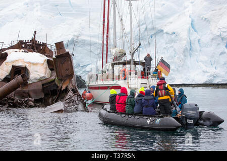 Zodiacs von Kreuzfahrtschiffen und Yachten zu einem alten shiprwrecked whaleing Boot in Wilhelmina Bay festgemacht, Graham Land, Antarktische Halbinsel. Stockfoto