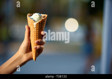 Eis in der Frau die Hand mit unscharfen Stadt bokeh Hintergrund und Copyspace. Isolierte Sicht, selektive konzentrieren. Sommer Thema. Eis schmelzen und Defr Stockfoto