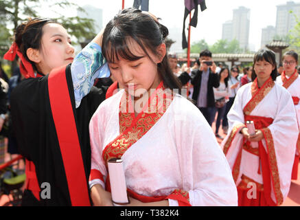 Xi'an, China. 7 Apr, 2019. Ein Mitarbeiter hilft, ein Student tragen die Haarnadel während einer traditionellen Coming-of-age-Zeremonie in Xi'an, die Hauptstadt der Nordwesten Chinas, April 7, 2019. 50 Schüler im Alter von 16-20 an der Coming-of-age-Zeremonie fand. Credit: Liu Xiao/Xinhua/Alamy leben Nachrichten Stockfoto