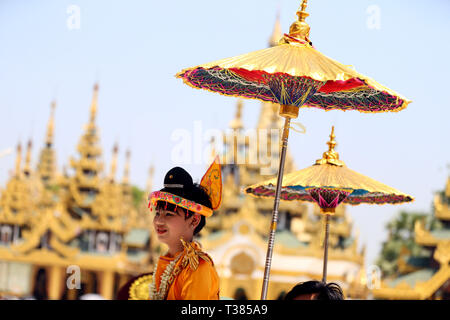 Yangon, Myanmar. 7 Apr, 2019. Ein kleiner Junge in traditionelle Kleidung besucht eine Parade während der Shinbyu novitiation Zeremonie an der Shwedagon Pagode in Yangon, Myanmar, April 7, 2019. Die Shinbyu novitiation Zeremonie ist ein wesentlicher Bestandteil im Leben eines Myanmar Buddhistischen männlichen unter dem Alter von 20 Jahren. Credit: U Aung/Xinhua/Alamy leben Nachrichten Stockfoto