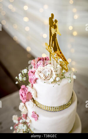 Hochzeitstorte mit weißen und rosa Zucker Blumen und gold Topper Stockfoto