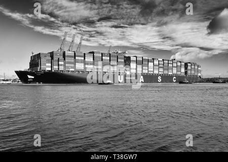 Schwarz-weiß-Foto von Schleppern, die das Containerschiff der Giant United Arab Shipping Company, AL ZUBARA, am Southampton Container Terminal, Großbritannien, führen. Stockfoto