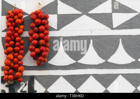 Kirsche Tomaten an der Wand aufhängen, in Pyrgi Chios Griechenland. Mit geometrischen Mustern Dekorationen auf den Gebäuden. Stockfoto