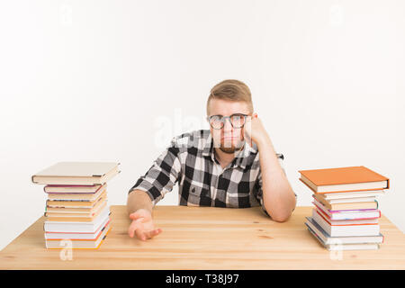 Menschen, Wissen und Bildung Konzept - Müde männliche Kursteilnehmer am Tisch sitzen mit Bergen von Büchern und will nicht bis zu studieren. Stockfoto