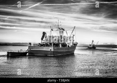 Zwei Fischtrawler verlassen den Hafen in den frühen Abend, Schwarz und Weiß classic Foto Stockfoto