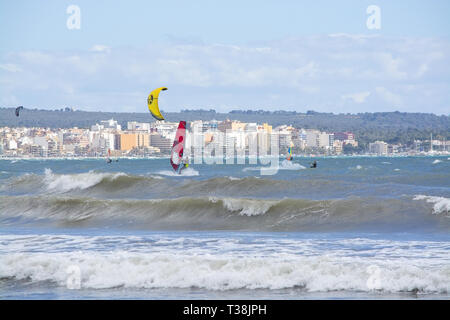CAN PASTILLA, MALLORCA, SPANIEN - 6. APRIL 2019: Surfer in die grünen Wellen spielen an einem windigen, sonnigen Tag am 6. April 2019 in Can Pastilla, Mallorca, Sp Stockfoto