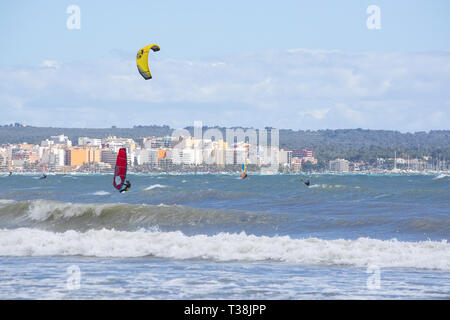 CAN PASTILLA, MALLORCA, SPANIEN - 6. APRIL 2019: Surfer in die grünen Wellen spielen an einem windigen, sonnigen Tag am 6. April 2019 in Can Pastilla, Mallorca, Sp Stockfoto