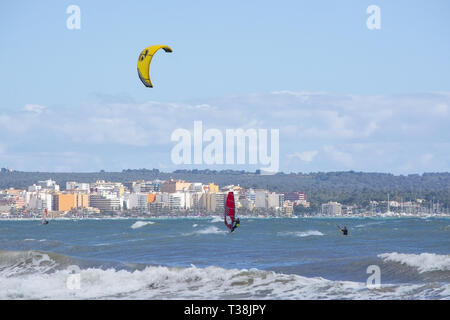 CAN PASTILLA, MALLORCA, SPANIEN - 6. APRIL 2019: Surfer in die grünen Wellen spielen an einem windigen, sonnigen Tag am 6. April 2019 in Can Pastilla, Mallorca, Sp Stockfoto