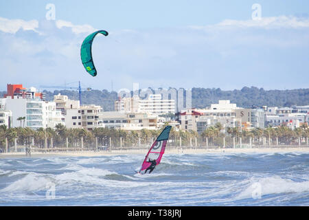 CAN PASTILLA, MALLORCA, SPANIEN - 6. APRIL 2019: Surfer in die grünen Wellen spielen an einem windigen, sonnigen Tag am 6. April 2019 in Can Pastilla, Mallorca, Sp Stockfoto