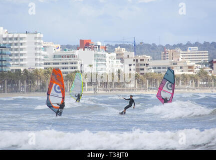 CAN PASTILLA, MALLORCA, SPANIEN - 6. APRIL 2019: Surfer in die grünen Wellen spielen an einem windigen, sonnigen Tag am 6. April 2019 in Can Pastilla, Mallorca, Sp Stockfoto