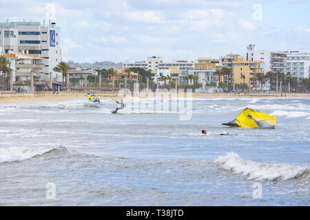 CAN PASTILLA, MALLORCA, SPANIEN - 6. APRIL 2019: Surfer in die grünen Wellen spielen an einem windigen, sonnigen Tag am 6. April 2019 in Can Pastilla, Mallorca, Sp Stockfoto