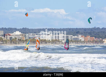 CAN PASTILLA, MALLORCA, SPANIEN - 6. APRIL 2019: Surfer in die grünen Wellen spielen an einem windigen, sonnigen Tag am 6. April 2019 in Can Pastilla, Mallorca, Sp Stockfoto