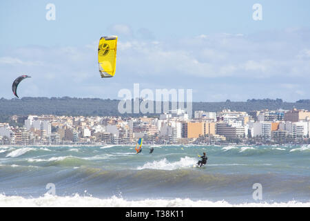 CAN PASTILLA, MALLORCA, SPANIEN - 6. APRIL 2019: Kitesurfer in die grünen Wellen spielen an einem windigen, sonnigen Tag am 6. April 2019 in Can Pastilla, Mallorca Stockfoto