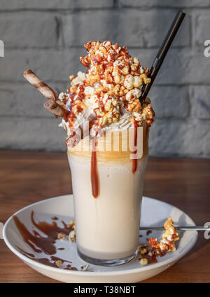 Milchshake mit Popcorn und Karamell auf dem Tisch Stockfoto