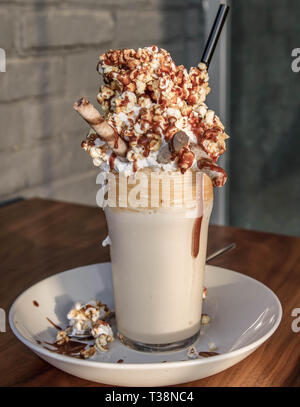 Milchshake mit Popcorn und Karamell auf dem Tisch Stockfoto