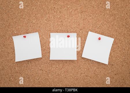 Drei weißen Aufkleber auf einer Pinnwand angeheftet. Stockfoto