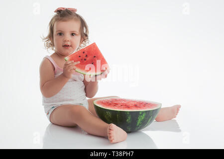 Baby Mädchen essen Wassermelone Slice auf weißem Hintergrund. Stockfoto