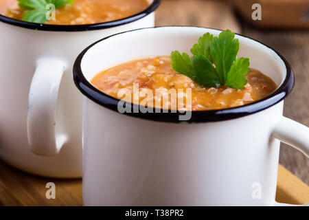 Vegan pearl Gerstensuppe mit Gemüse der Saison in ländlichen Tassen auf rustikalen Holztisch, pflanzliche Lebensmittel, Nahaufnahme, selektiver Fokus Stockfoto