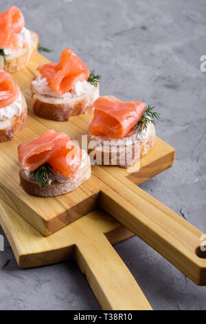 Party Food, Vorspeise mit Lachs, Pastete und geräuchertem Lachs auf Holz Schneidebrett, Snack platter auf grauem Hintergrund close-up, selektiver Fokus Stockfoto