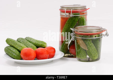 Hausgemachte Konserven: eingemachte Tomaten und Gurken im Glas vor weißem Hintergrund Stockfoto