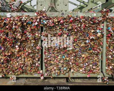 Köln, Deutschland, 6. April 2019. Unzählige bunte Vorhängeschlösser von Liebhabern auf einem Zaun auf der Hohenzollern Brücke links Stockfoto