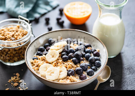 Müsli, Früchte, Beeren in der Schüssel auf Schwarz konkreten Hintergrund. Gesundes Frühstück Müsli. Konzept der Diäten, gesunde Ernährung, sauberes Essen Stockfoto