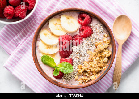 Rosa Smoothie Schüssel mit Banane, Himbeer, Müsli und Chia Samen. Gesunde vegane oder vegetarische Smoothy Schüssel, Ansicht von oben Stockfoto
