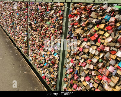 Köln, Deutschland, 6. April 2019. Unzählige bunte Vorhängeschlösser von Liebhabern auf einem Zaun auf der Hohenzollern Brücke links Stockfoto