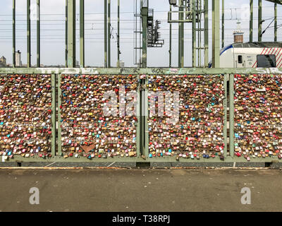 Köln, Deutschland, 6. April 2019. Unzählige bunte Vorhängeschlösser von Liebhabern auf einem Zaun auf der Hohenzollern Brücke links Stockfoto
