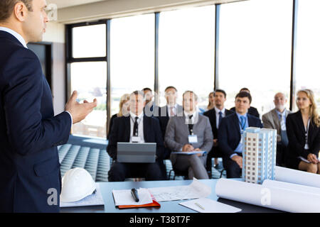 Zielgruppe Geschäftsleute und Investoren bei der Präsentation Zimmer sitzen, Konferenzsaal, Ansicht vom Lautsprecher Tabelle mit Blueprints, Modell der modernen mult Stockfoto