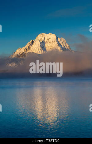 Eine dicke Schicht von Nebel, die sich auf der Basis des Mount Moran und aus der Jackson Lake an einem kalten Wintermorgen. Der Grand Teton National Park, Wyoming Stockfoto