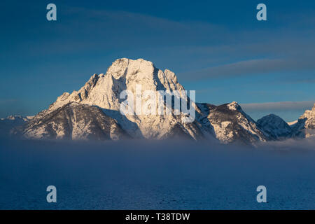 Mount Moran steigen über eine Schicht von Nebel obscurring die Grenze zwischen der Basis der Teton Mountains und Jackson See. Der Grand Teton National Park, W Stockfoto