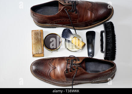 Ein ziemlich verwendet Paar braune Schuhe mit Schuhcreme, Bürste, Schuhspanner, Fuß Füller und anderes Zubehör Stockfoto