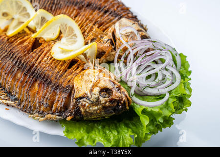 Gegrillter karpfen fisch auf dem weißen Teller über Weiß Stockfoto