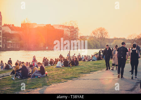 Berlin, Deutschland - April, 2019: die Menschen am Flußufer an der Berliner Mauer/East Side Gallery bei Sonnenuntergang in Berlin, Deutschland Stockfoto