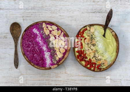 Zwei Smoothie in Kokosnuss Schalen mit Dragon Obst-, Avocado-, Mandel- flocken, coconut Chips, Goji Beeren und Chia Samen zum Frühstück, bis zu schließen. Die Konz Stockfoto