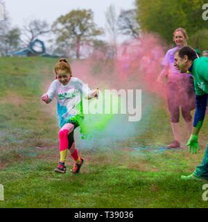 Junge Mädchen runner Lachen und in Farbe auf Macmillan Cancer Charity 5K Farbe Fun Run abgedeckt. Stockfoto