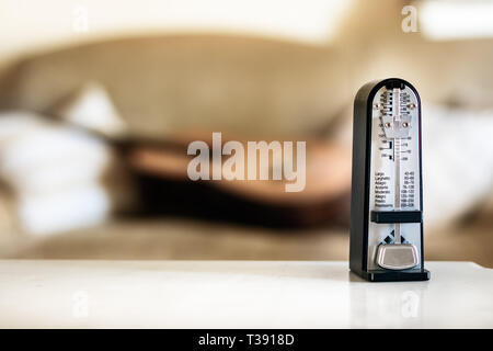 Mechanische Metronome in Bewegung, über eine hölzerne klassische Gitarre Hintergrund. Stockfoto