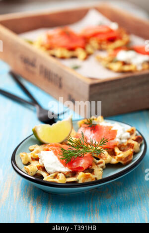 Kartoffel Waffeln mit Lachs, Frischkäse auf einem blauen Hintergrund aus Holz. Stockfoto