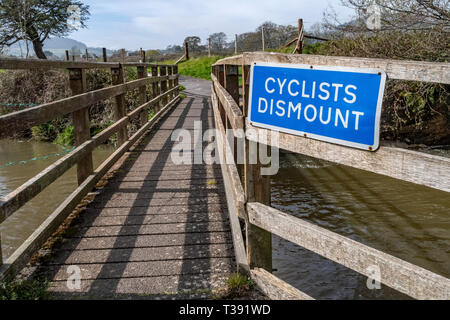 Radfahrer Abbauen anmelden Bekanntmachung über eine Fußgängerbrücke über den Fluss Ffa bei Fortescue, Plymouth, Devon, Großbritannien Stockfoto