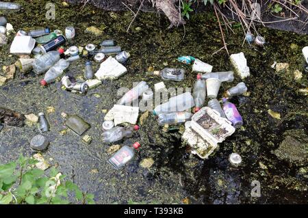 Nahaufnahme der verworfenen allgemeine Müll in eine wässrige Entwässerungsgraben Stockfoto