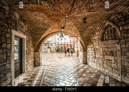 Das Quadrat der Arme öffnet sich vor wie Touristen die gated, ummauerten mittelalterlichen Festung Stadt Kotor, Montenegro geben Sie über den Tunnel Eingang Stockfoto