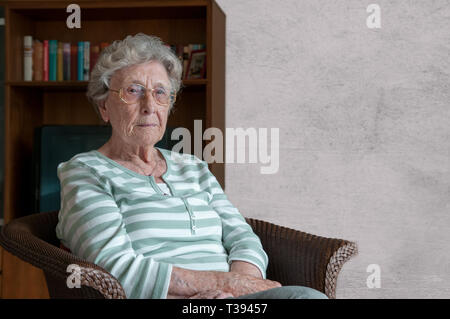 Einsame ältere Frau im Sessel sitzen Stockfoto