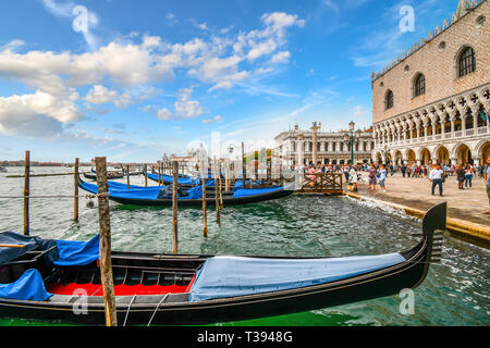 Die Gondeln Grand Canal Station als Touristen von der Dogenpalast und der Markusplatz mit der Santa Maria della Salute Dome hinter Pass Stockfoto