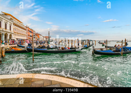 Touristen füllen die Gondeln auf dem Canal Grande Station als Besucher der Riva Degli Schiavoni Geschäfte und Cafés entlang der Promenade in Venedig Italien genießen Stockfoto