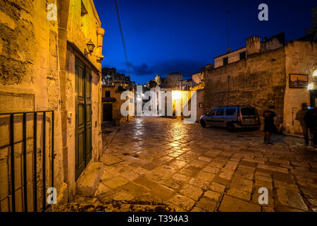 Ein Hund steht unter einer Straßenlaterne in der Ferne bis spät in die Nacht in der Altstadt von Matera, Italien Stockfoto